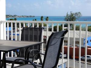 two chairs and a table on a balcony with the ocean at Oistins Bayview Apartments in Christ Church