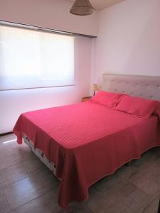 1 dormitorio con cama roja y ventana en Edificio Familiar Mar Veo en Villa Gesell