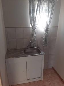 een badkamer met een wastafel en een raam met gordijnen bij OrbanLife Lite Keetmanshoop in Keetmanshoop