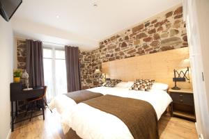 a bedroom with a large bed and a stone wall at Casa Nicolasa in Donostia-San Sebastián