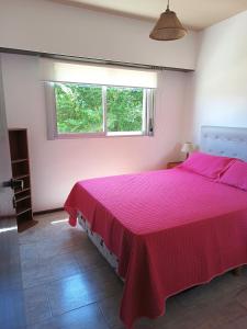 una camera con letto rosa e finestra di Edificio Familiar Mar Veo a Villa Gesell