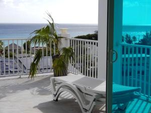 a porch with a bench and the ocean in the background at Oistins Bayview Apartments in Christ Church