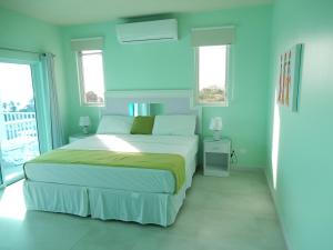 a bedroom with a large bed with blue walls at Oistins Bayview Apartments in Christ Church