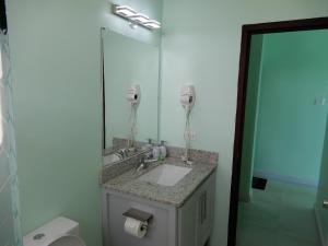 a bathroom with a sink and a mirror and a toilet at Oistins Bayview Apartments in Christ Church