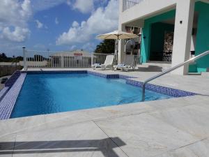 a swimming pool with two chairs and an umbrella at Oistins Bayview Apartments in Christ Church