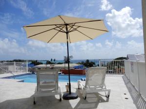 two chairs and an umbrella on a patio at Oistins Bayview Apartments in Christ Church