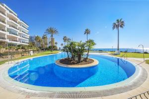 a large pool with palm trees in a resort at Apartamento Mi Capricho in Mijas Costa