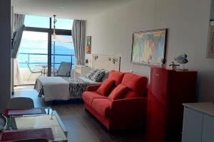 a living room with a red couch and a bed at El Roquete, Feel the Sea in Gáldar