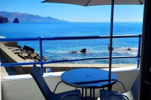 a chair and an umbrella on a balcony with the ocean at El Roquete, Feel the Sea in Gáldar