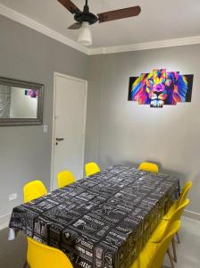 uma sala de jantar com uma mesa e cadeiras amarelas em Apartamento na Praia da Enseada - Guarujá SP no Guarujá