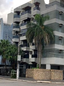 um edifício alto com palmeiras em frente em Apartamento na Praia da Enseada - Guarujá SP no Guarujá