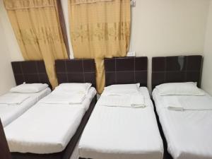 eine Reihe von Betten in einem Zimmer mit Fenstern in der Unterkunft Hotel Ocean in Lahad Datu