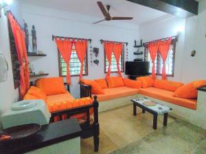 una sala de estar con muebles de color naranja y cortinas de color naranja. en Villa 36 Karibuni en Malindi