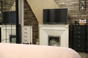 ein Schlafzimmer mit einem Kamin und einem TV darüber. in der Unterkunft Maison charmante à Arques-la-Bataille avec terrasse et cheminée. in Arques-la-Bataille