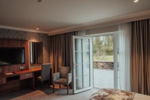 a hotel room with a desk with a television and a sliding glass door at Dunadry Hotel And Gardens in Antrim