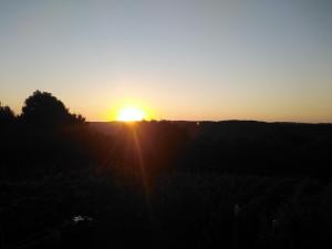 un coucher de soleil au-dessus d'un champ et un coucher de soleil en arrière-plan dans l'établissement Sobe Sky, à Fužine