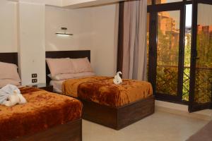 a hotel room with two beds and a window at ASWAN NILE PALACE (swimming pool-rooftop-Nile view) in Aswan