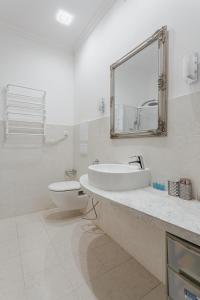 a bathroom with a sink and a toilet and a mirror at Sea Breeze Apartments in Odesa