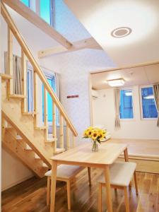 ein Esszimmer mit einem Tisch und einer Treppe in der Unterkunft Opopo home 堺町店 in Otaru