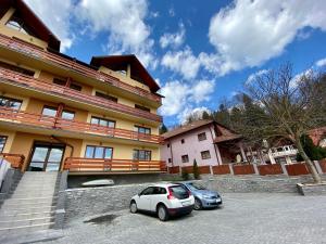 two cars parked in a parking lot in front of a building at Alsama Zurqa in Buşteni