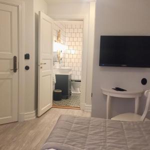 a bathroom with a toilet and a television on a wall at Hotell Hamngatan 27 in Falkenberg