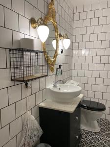 a bathroom with a sink and a mirror and a toilet at Hotell Hamngatan 27 in Falkenberg