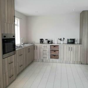 Manz' amahle Guest Cottage في هارتبيسبورت: مطبخ مع خزائن خشبية وأرضية من البلاط الأبيض