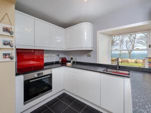 a kitchen with white cabinets and a large window at Charming Cottage in North Berwick with Sea Views in North Berwick