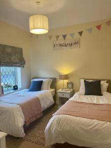 a bedroom with two beds and a chandelier at Bronte Bungalow - In Beautiful Bronte Country! in Oxenhope