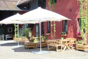 eine Terrasse mit Tischen und Sonnenschirmen vor einem Gebäude in der Unterkunft Gut Huthmacherhof in Jülich