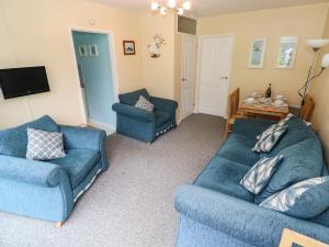 un soggiorno con due divani blu e una TV di Number 6 Oxwich Leisure Park a Swansea