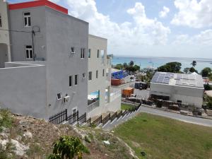 a building on a hill with the ocean in the background at Oistins Bayview Apartments in Christ Church