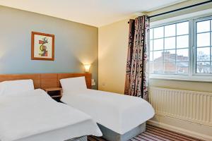 two beds in a room with a window at OYO Shilton Inn in Earl Shilton