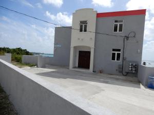 a white building with a red roof next to the ocean at Oistins Bayview Apartments in Christ Church