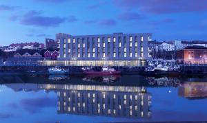 un gran edificio con su reflejo en el agua en Tŷ Milford Waterfront en Milford Haven