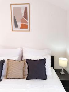 ein weißes Bett mit Kissen und einem Bild an der Wand in der Unterkunft Central Apartment Ira in Korčula