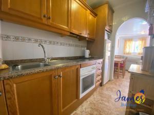 uma cozinha com armários de madeira e um lavatório em La Cinuelica R2, Ground Floor Apartment with Comm Pool L167 em Orihuela