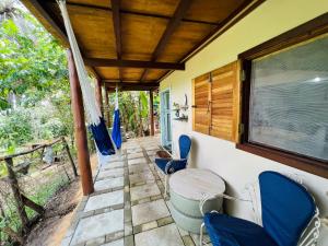 a porch of a house with chairs and a table at Eco Casa di Barro Hospedagem e Hostel in Ilha de Boipeba