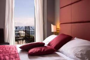 a bedroom with a bed with two pillows and a window at Hotel Ligure in Alassio