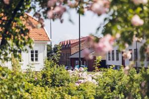 a white house with a red roof and some flowers at Hotell Hamngatan 27 in Falkenberg