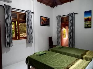 a bedroom with two green beds and a window at Machan Villa in Tangalle