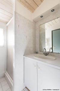 La salle de bains blanche est pourvue d'un lavabo et d'un miroir. dans l'établissement Maison Aumière, à La Flotte