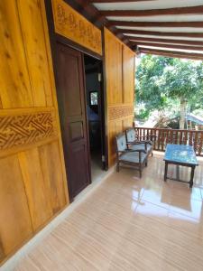 a porch with a chair and a table and a door at jala sutra cottages in Giri