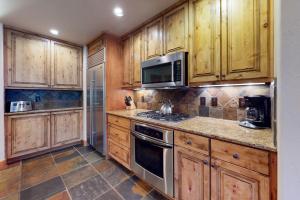 a kitchen with wooden cabinets and stainless steel appliances at Antlers in Steamboat Springs +14 photos