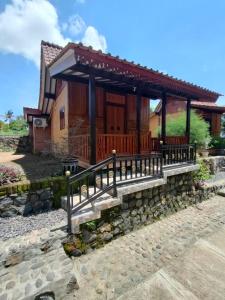a small house with a porch and a stone wall at jala sutra cottages in Giri