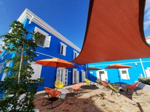 un edificio blu con sedie e ombrelloni di fronte di The Freedom Hotel a Willemstad