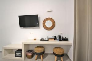 a desk with two chairs and a tv on a wall at Kleri's apartments 5 in Tinos Town