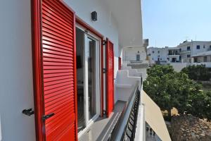 a window with red shutters on a building at Kleri's apartments 5 in Tinos Town