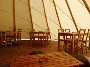 a room with wooden tables and chairs in a tent at Nomad Planet in Fiães do Rio