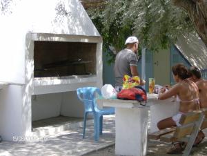 a group of people sitting at a table with a pizza oven at Camping Koula in Parikia